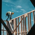 A construction worker is climbing up the side of a building.