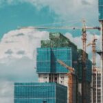 A building under construction with cranes in the background.