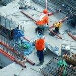 A group of construction workers standing on top of a building.