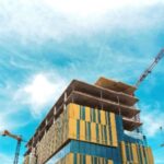 A building under construction with cranes in the background.